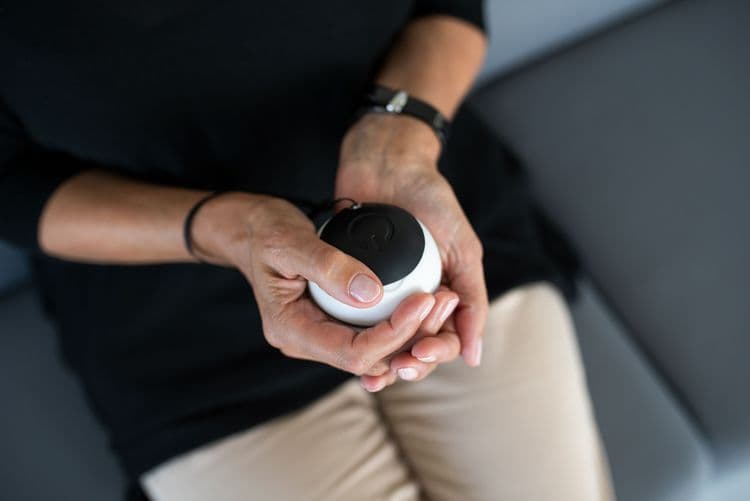 Person with slim build holding a Vilim Ball before them in both hands, looking down into their lap.