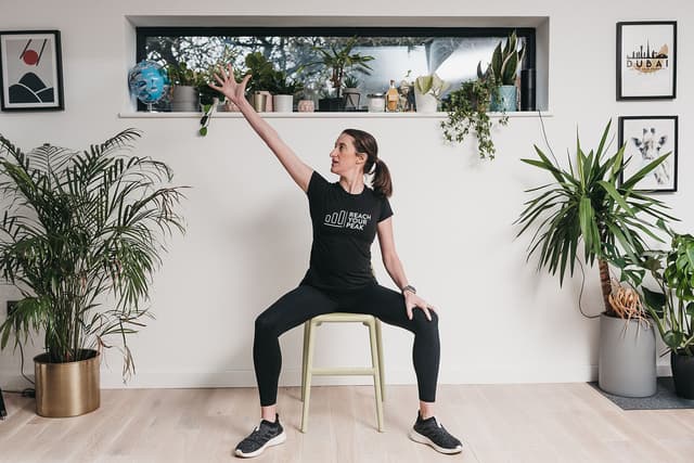 A photo of a physiotherapist demonstrating a seated exercise.