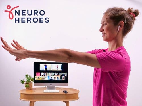 A photo of a physiotherapist conducting an online exercise class. The Neuro Heroes logo is in the top left corner.