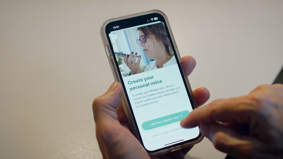 Someone using the app to "Create your personal voice", holding a smartphone in their hands.