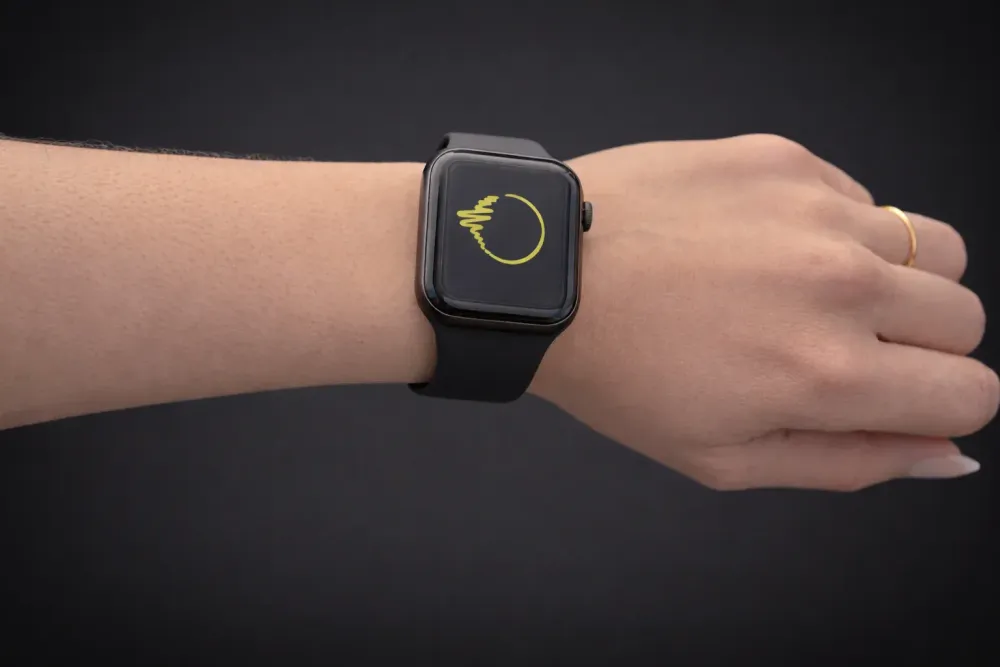 A photo of a white arm. They are wearing an black Apple Watch with the yellow-green BeechBuddy logo on the screen.