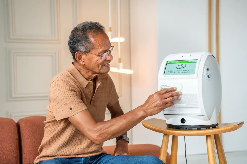 A photo of a man pressing the green lit button on his Evondos device to dispense his medication.