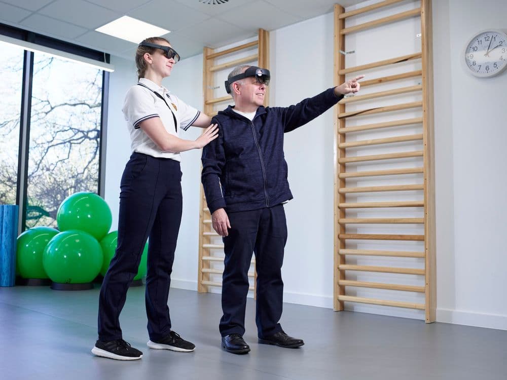 A photo of a man with his physiotherapist. They are both wearing the Strolll Reality DTx headset.