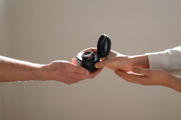 Photo of two people reaching out and holding the CUE1+ in its carry case in the Deep Ocean colour option.