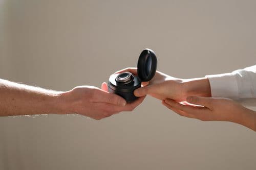 Photo of two people reaching out and holding the CUE1+ in its carry case in the Deep Ocean colour option.