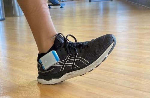 Close-up photo of someone wearing Heel2Toe clipped to their trainer as they walk.