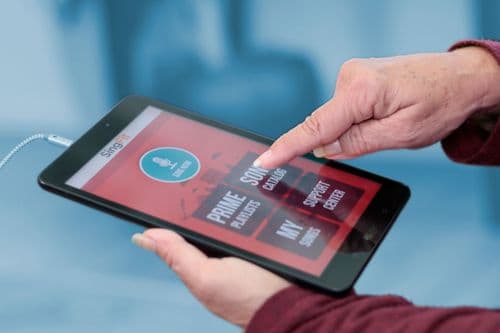 A photo of a hand holding a tablet. The screen shows the SingFit app.