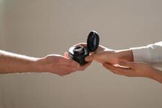 Photo of two people reaching out and holding the CUE1+ in its carry case in the Deep Ocean colour option.