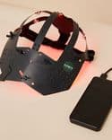 Symbyx Neuro on a table. It is strips of black plastic in a hat shape connected to a black box.