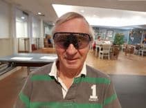 A white man with grey hair and a grey/green shirt wears StrydAR glasses, looking at the camera.
