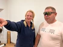 A white man with short hair is introduced to the StrydAR glasses by a blonde woman.