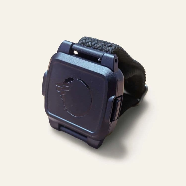 A photo of the BeechBand 100E sat on a surface with a yellow background. The device is dark blue and engraved with the BeechBand logo.